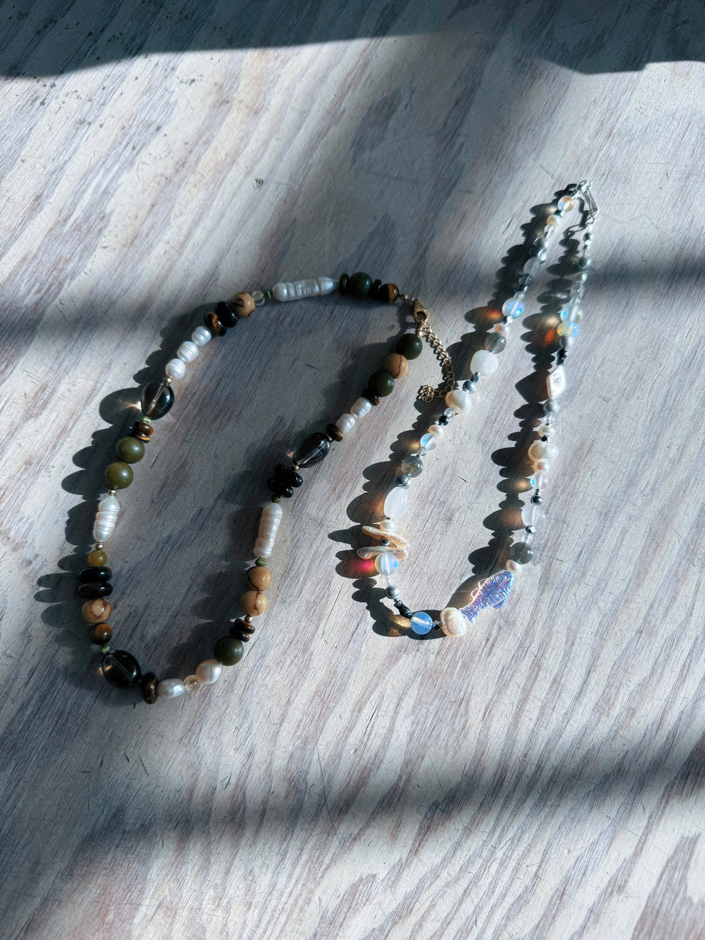 Two necklaces with beads on a wooden surface.