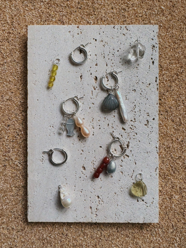 Collection of various earrings on a textured stone surface