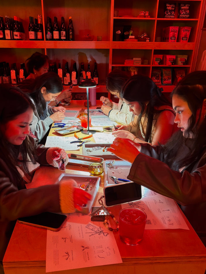 Group of people sitting around a table with red lighting, engaged in DIY.