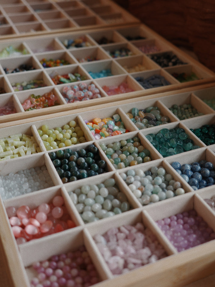 Wooden box with compartments filled with various colored beads.