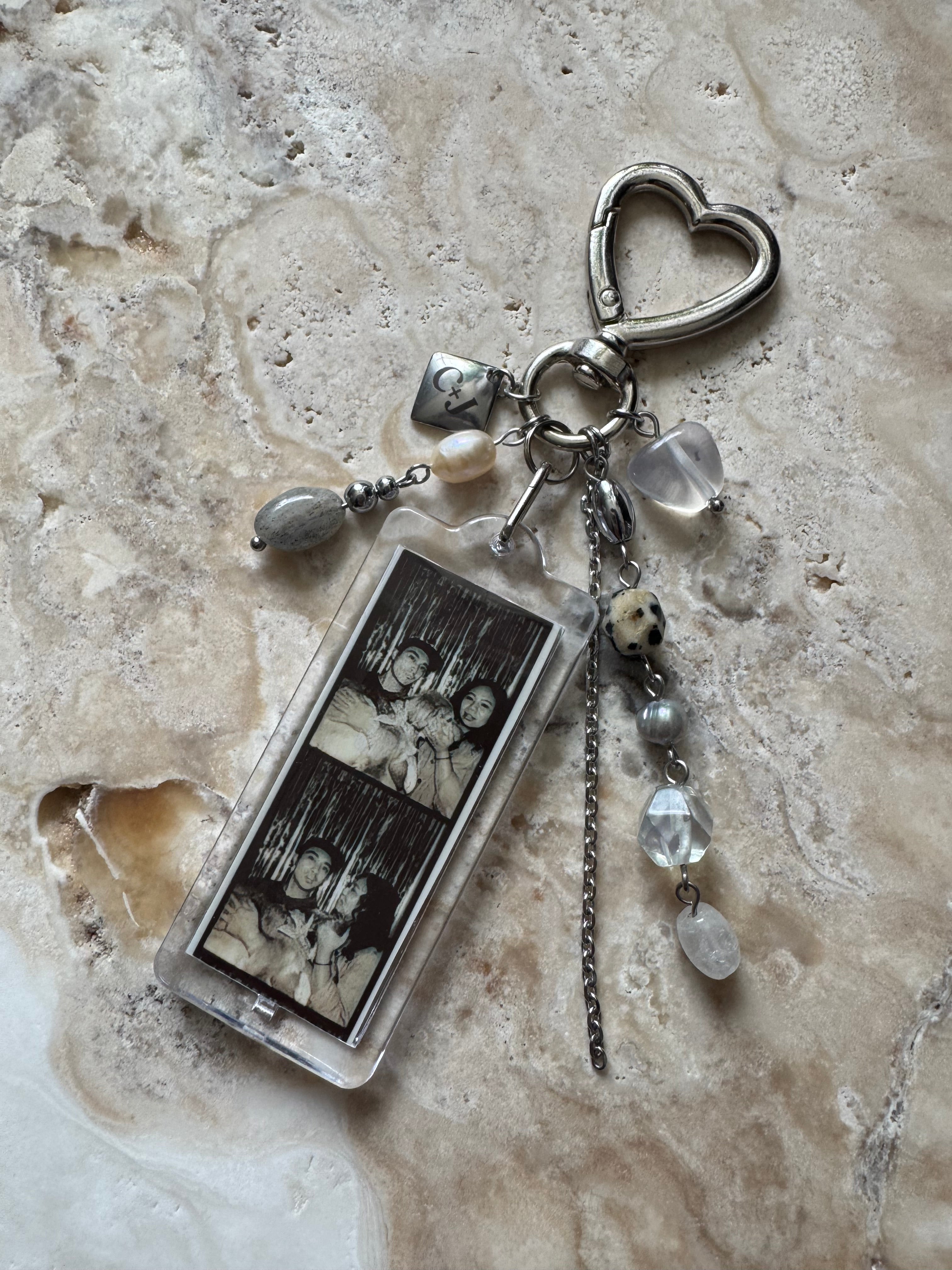 Keychain with heart-shaped charm and photo charm on a textured surface