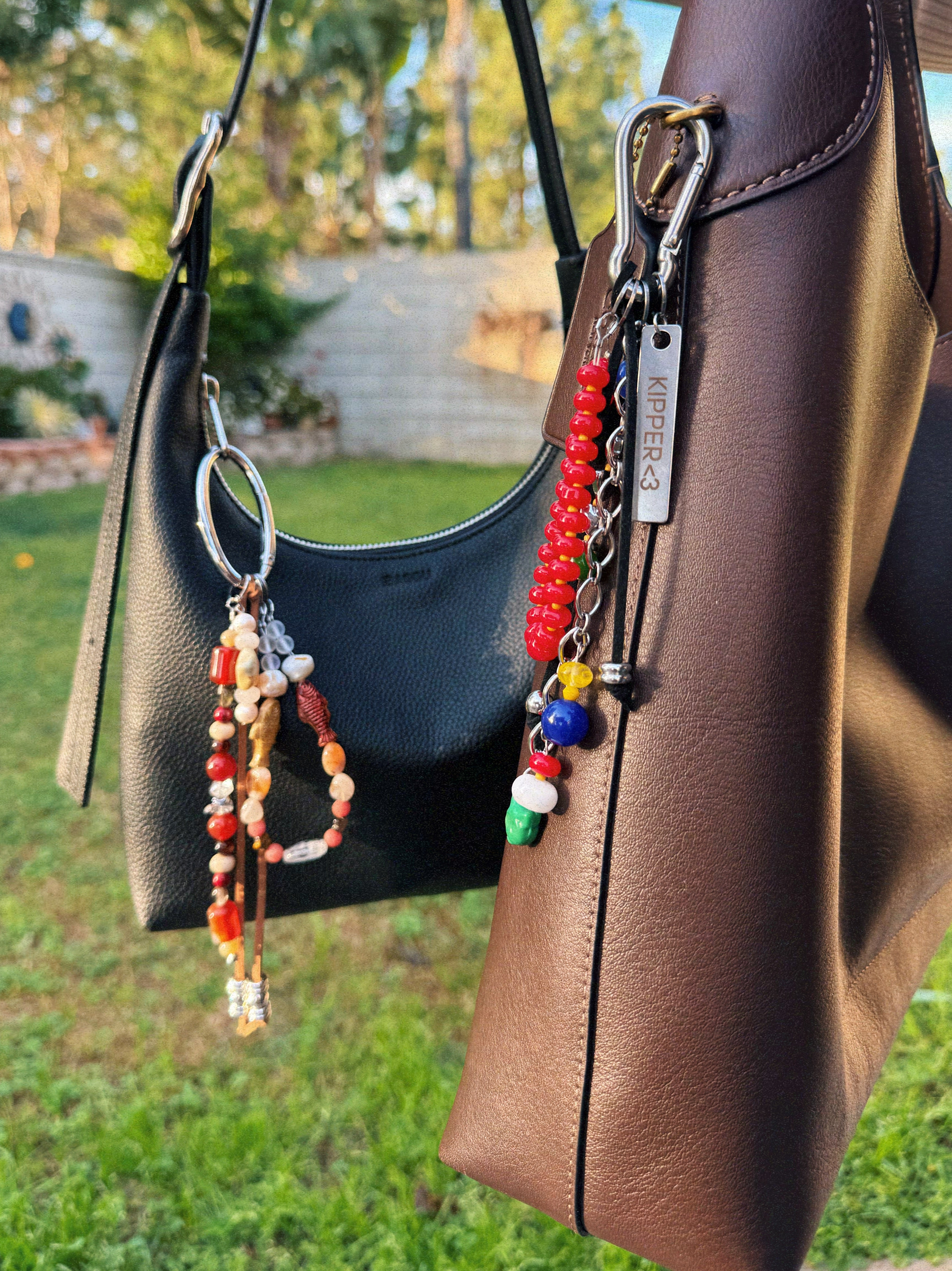 Brown leather handbag with colorful beaded charms on a grassy outdoor background
