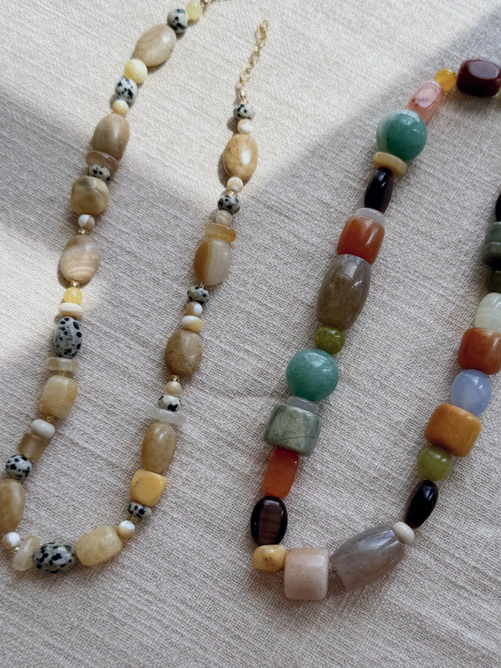 Two beaded necklaces on a textured fabric background