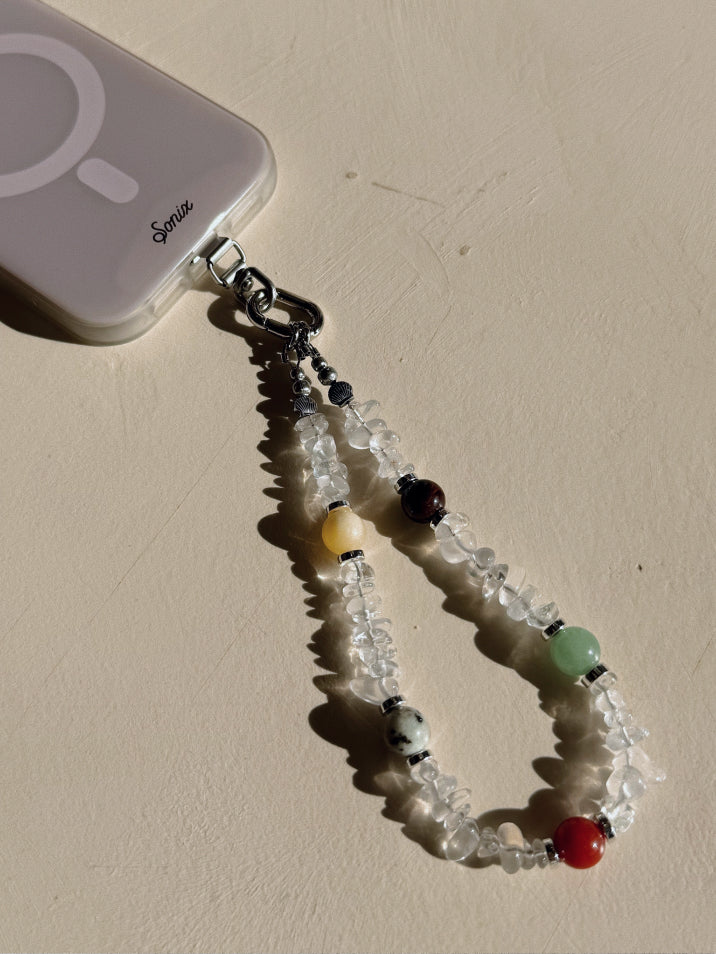 Beaded phone charm attached to a phone case on a beige surface